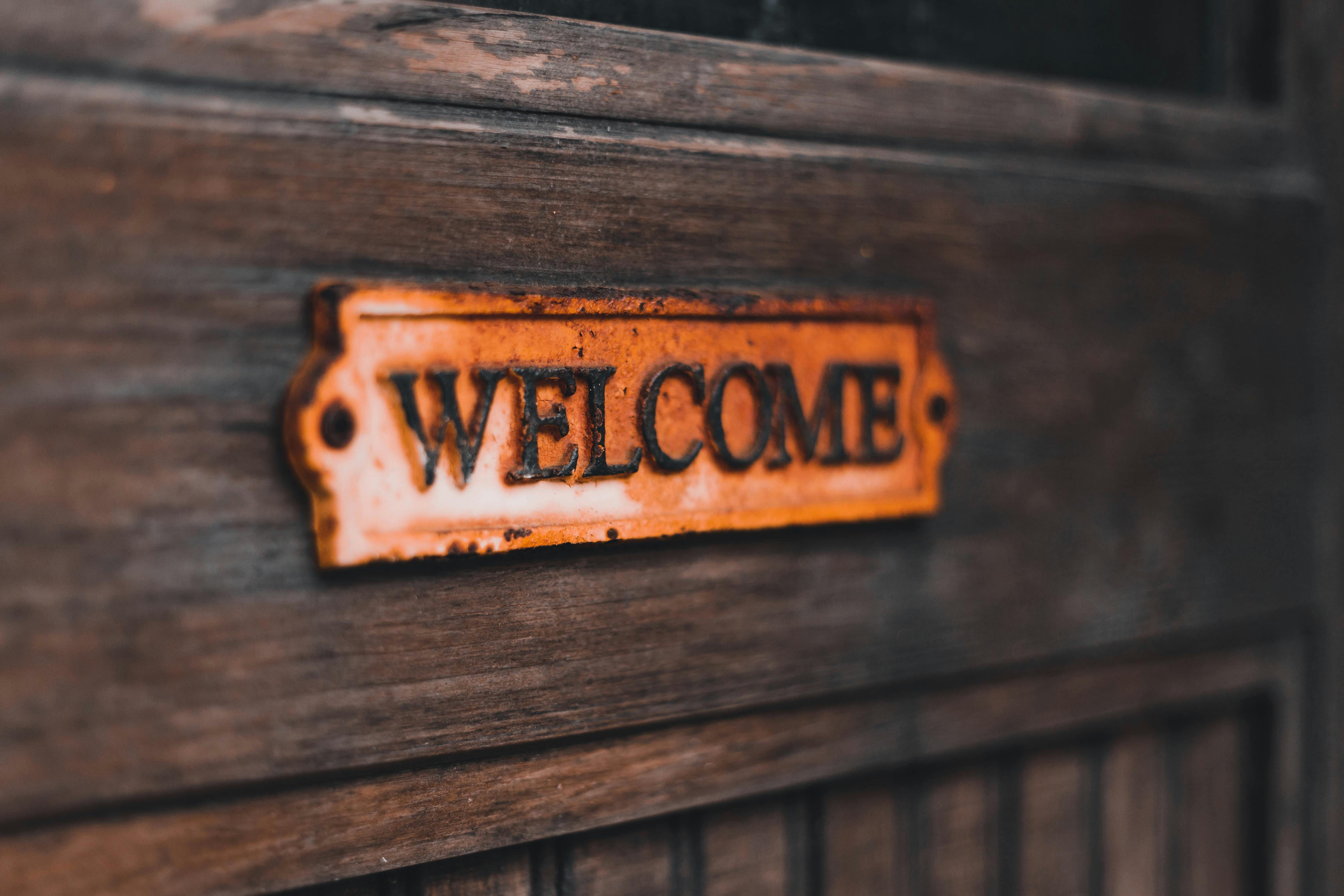 Close-up of a rusty vintage welcome sign on a wooden surface, creating a warm, rustic feel.