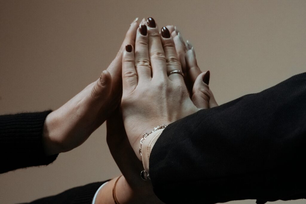 Four hands coming together in unity, showcasing solidarity and teamwork.