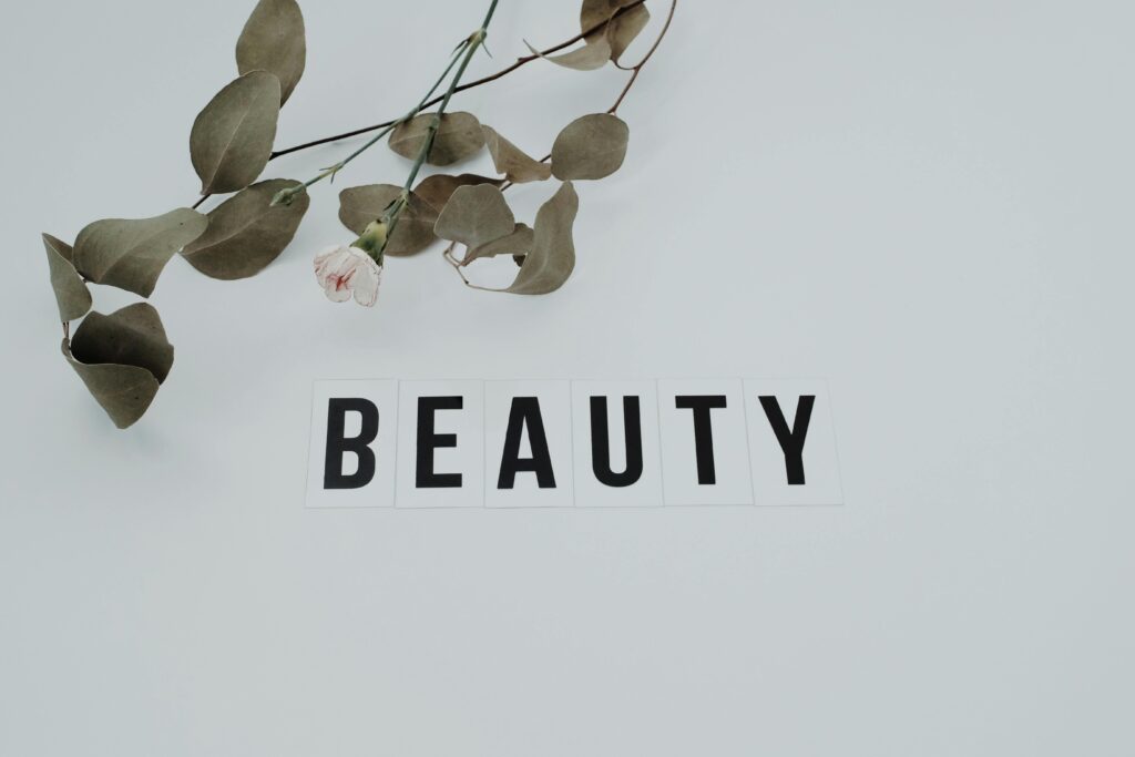 A minimalist image featuring an eucalyptus branch with the word 'BEAUTY' on a white background.